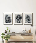 Set of three black and white oil paintings hanging above a bed