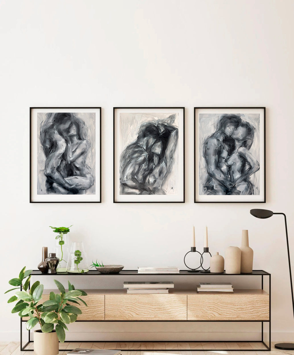Set of three monochrome figurative paintings on a light wall
