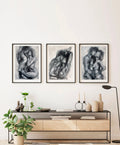 Set of three monochrome figurative paintings on a light wall