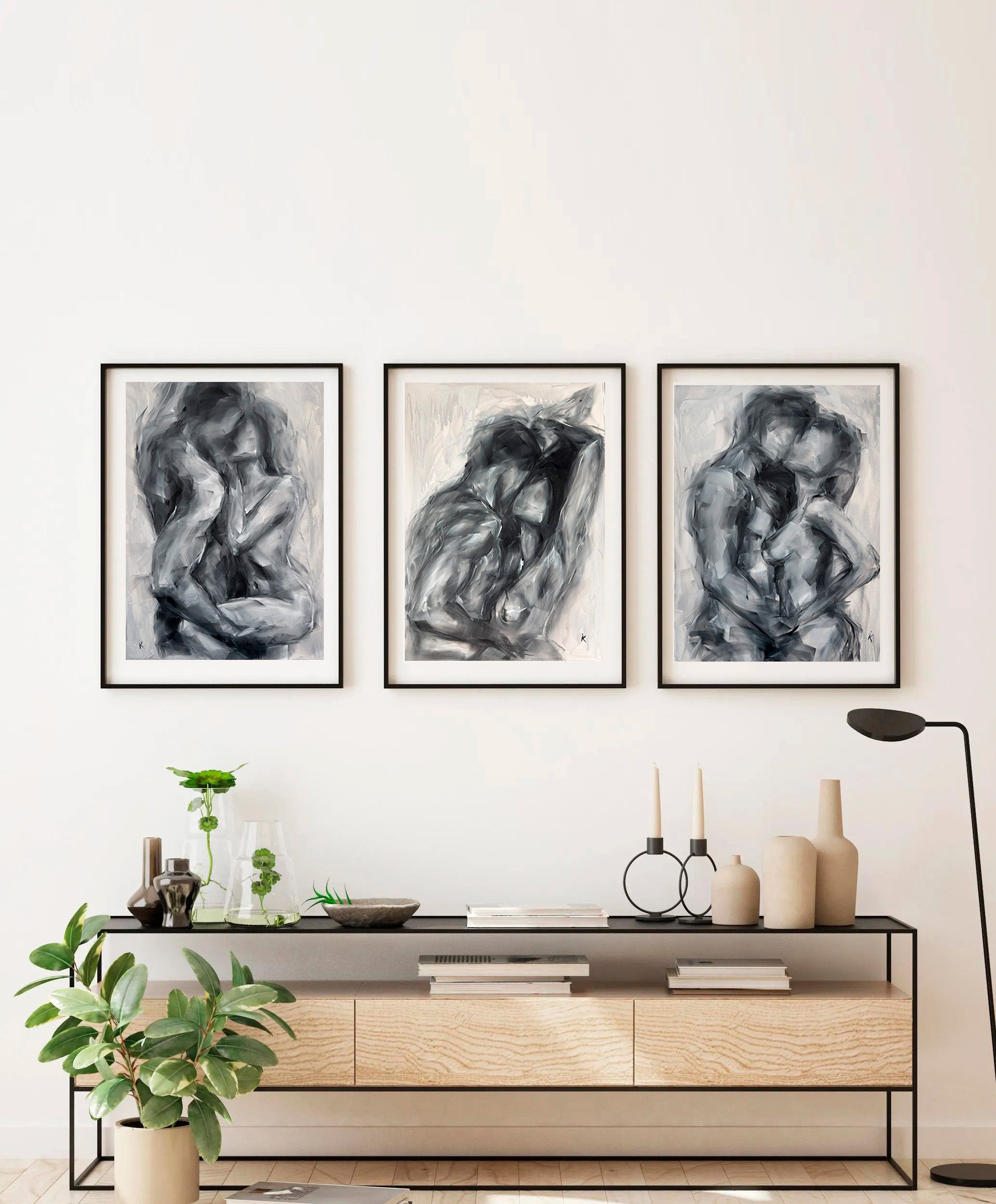 Set of three monochrome figurative paintings on a light wall