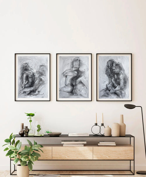 Set of three monochrome figurative paintings on a light wall